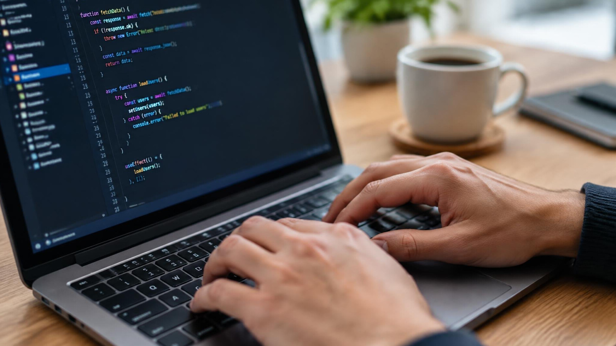 Close up of hands typing code on a laptop keyboard