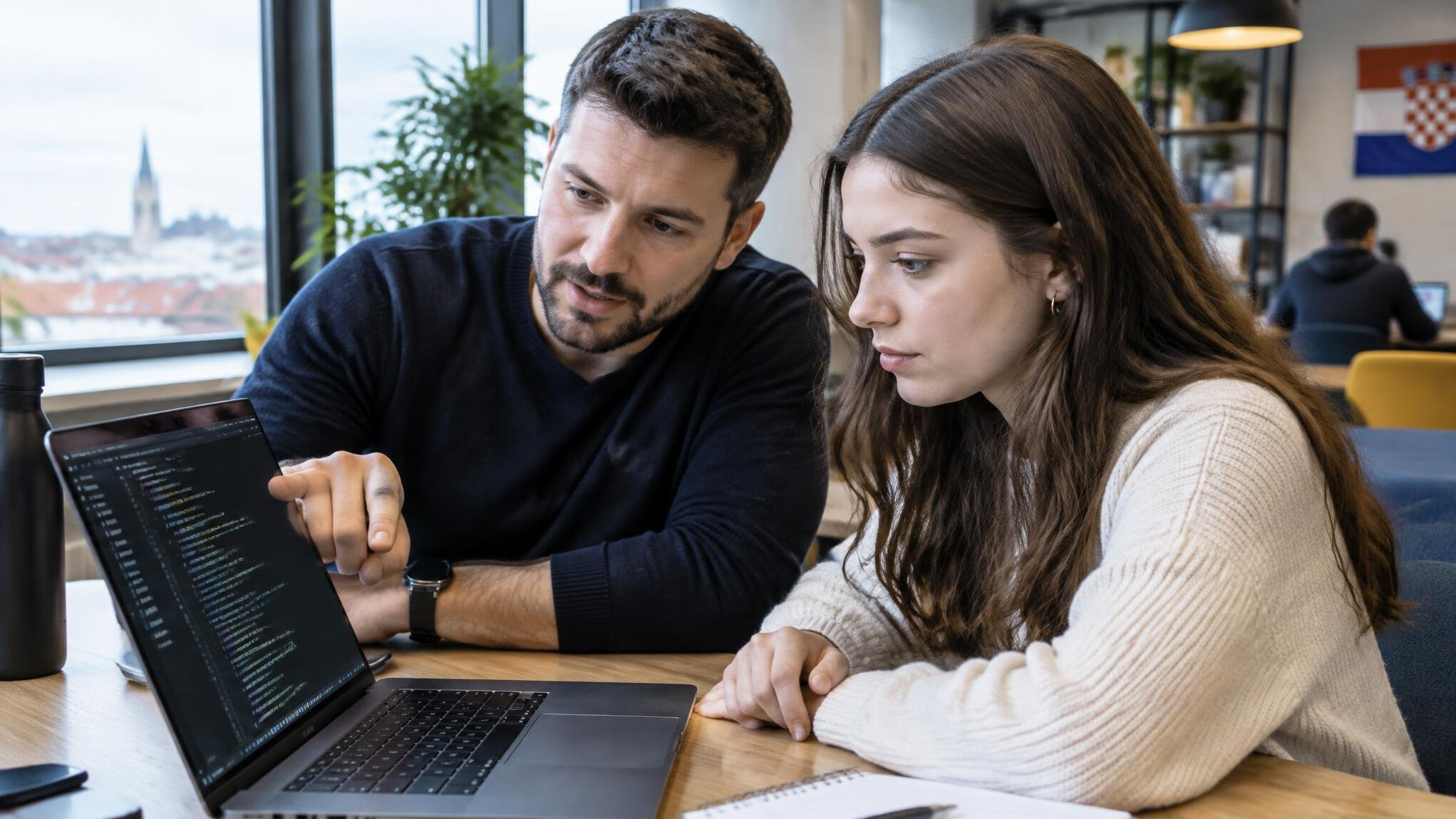 Mentor helping a student with code on a laptop